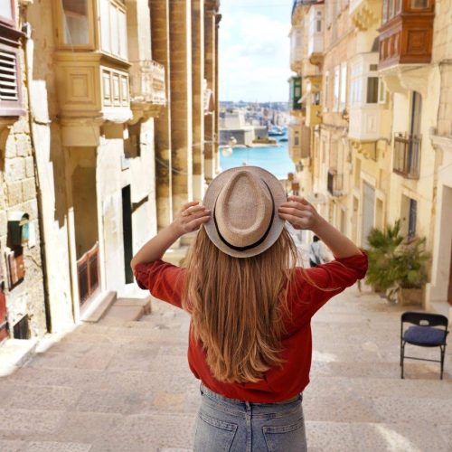 tourism-malta-back-view-tourist-girl-holding-hat-descends-stairs-old-town-valletta-unesco-world-heritage-malta